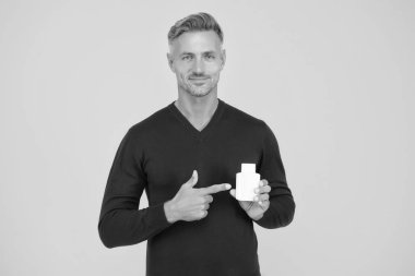 Denemeye değer. Erkekler için makyaj malzemeleri. Güzellik ürünü. Yakışıklı, bakımlı, sağlıklı bir adam ürün öneriyor. Vücut bakımı. Ürünü sunuyorum. Olgun adam şişeyi işaret ediyor. Tıraş olduktan sonra favori losyon