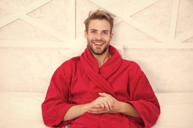 Bornozcu adam rahatlıyor. Uykuya dalmadan önce rahatlamak. Her gece yeterince uyuyun. Genel sağlık için gerekli tutarlı sirkadiyen ritim bakımı. Adam yakışıklı adam yatakta rahatlatıcı