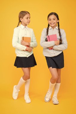 Geleceği oku. Sevimli küçük çocuklar kütüphaneden okumak için sarı arka planda kitaplar aldılar. Okumayı okulda öğrenen sevimli küçük kızlar. Okuyabiliriz.