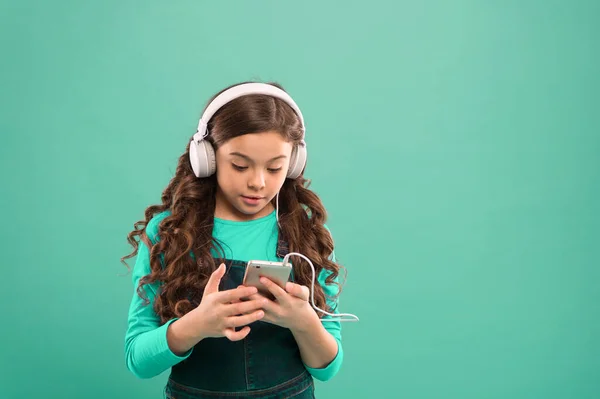 Rozrywka online. Darmowe aplikacje muzyczne. Słuchaj za darmo. Zdobądź subskrypcję konta muzycznego. Mała dziewczynka dziecko słuchać muzyki nowoczesne słuchawki i smartfon. Ciesz się muzyką. Ciesz się doskonałym dźwiękiem — Zdjęcie stockowe