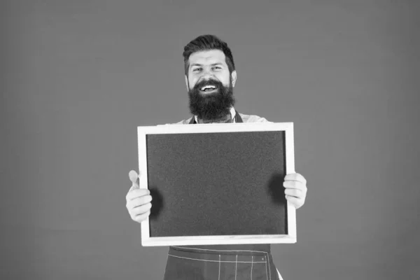 Um olhar amigável. Homem barbudo chalkboard, espaço de cópia. Empregado brutal na cozinha. homem maduro fundo vermelho. Barman hipster feliz. O que cozinhar. Menu de restaurante. anúncio de loja de café. Horas felizes — Fotografia de Stock