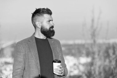 Kafein bağımlısı. Hippi bardağı kafein enerji içeceğiyle birlikte tutar. Sakallı adam açık havada sıcak kafeinli içecekle şarj oluyor. Sabah kafeinle daha iyi olur.