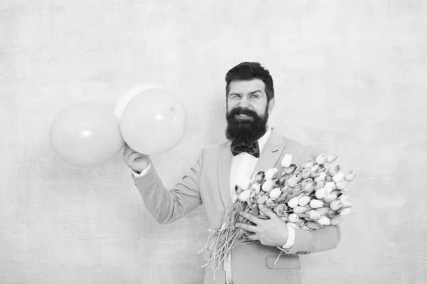 Flowers delivery. Gentleman romantic date. Birthday greetings. Confidence and charisma. Man bearded gentleman suit bow tie hold air balloons and bouquet. Gentleman making romantic surprise for her — Stock Photo, Image
