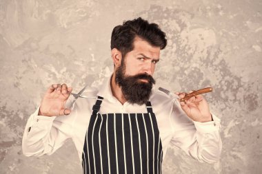 Berber aletleri. Kuaför önlüklü, bıçak ve makaslı berber. Yüz kılları. Sakallı berber tıraş oluyor. Sakal ve bıyık. Profesyonel saç kesimi. Berber dükkanı müdürü. Saç stili konsepti