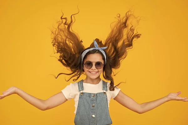 Sentindo-se bem cabelo fabuloso. Menina adorável com cabelo encaracolado acenando no fundo amarelo. Pequeno modelo de cabelo com aparência de moda. Menina bonito pequeno com cabelos longos morena. Cabeleireiros ou salão de beleza — Fotografia de Stock