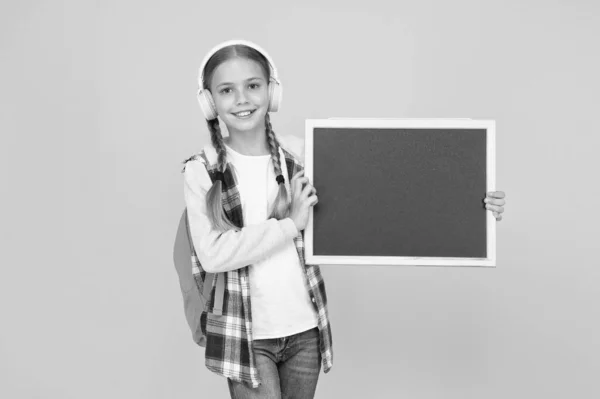 ここを見て陽気な女の子は黒板を保持します。学校のコンセプトに戻る。現代の学校生活。女子高生から連絡です女子高生は黒板のコピースペースを持っている。発表及び推進 — ストック写真