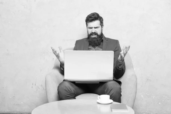 Tener algunos problemas en el trabajo. Hipster bebiendo café y trabajando en la estación de trabajo de computadoras. Hombre barbudo haciendo su trabajo en línea. Trabajar globalmente a distancia — Foto de Stock