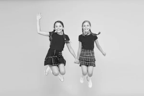 Helt enkelt vara runt. engelsk stil mode. lyckliga små flickor i rutig kjol. skönhetslook. lyckliga barn. barndoms glädje. trendig skoluniform. roligt hopp. röda mode flickor — Stockfoto