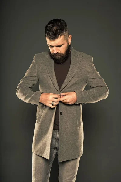 Dressing as fashionable man. Fashionable look of vogue model on grey background. Bearded man buttoning fashionable jacket. Fashionable hipster wear casual style
