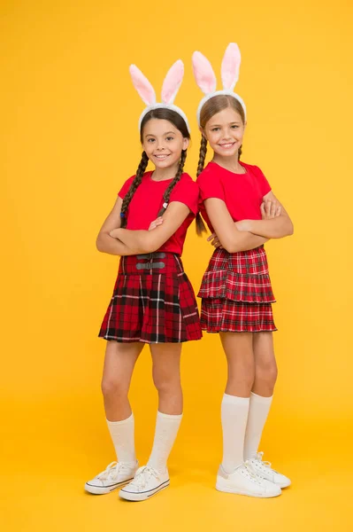 Joyeux Pâques. Joli lapin. Concept de divertissement et d'événement. Vacances de printemps. Enfants dans les oreilles de lapin lapin. Famille et fraternité. Petites écolières même uniforme scolaire avec de longues oreilles de lapin — Photo