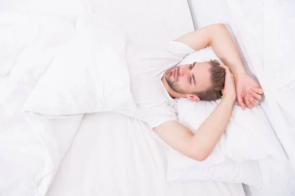 Sfaturi care promovează obiceiurile sănătoase de somn. Un bărbat chipeş se relaxează în pat. Stabiliți un tipar regulat de somn de noapte. Practicați activități calmante, cum ar fi meditația înainte de culcare. Conceptul de somn sănătos — Fotografie, imagine de stoc