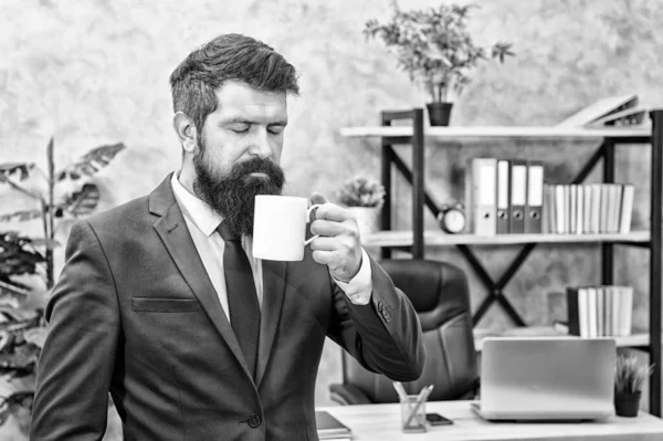 Drinking coffee relaxing break. Boss enjoying energy drink. Start day with coffee. Successful people drink coffee. Caffeine addicted. Man bearded businessman hold coffee cup stand office background — Stock Photo, Image