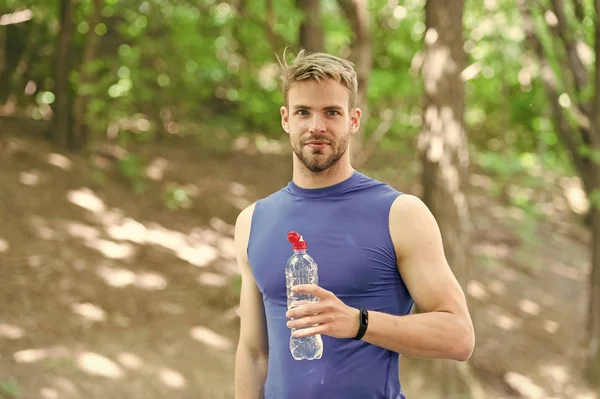 Освежающий напиток. Мужчина спортсмен держит бутылочную воду. Спортсмен пьет воду после тренировки в парке. Витамины и минералы. Мужчина спортивная одежда заботится о водном балансе. Здоровый образ жизни — стоковое фото