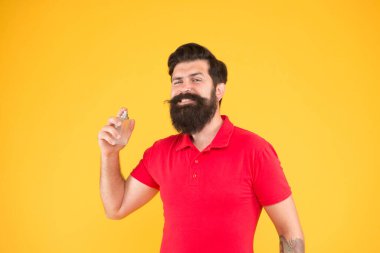 Losyon ve sprey. Parfüm ürünleri konsepti. Sakallı, yakışıklı adam şişe parfümü kullanıyor. Parfüm sürmüş. Erkeklere göre parfüm seç. Gün boyunca taze kokmasını sağla.