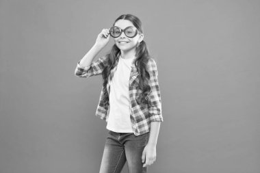 Gözlükler onun tarzı için mükemmel. Küçük çocuk moda gözlük mutlu görünüyor. Küçük çocuk turuncu arka planda parti gözlükleri ile gülümsüyor. Renk filtresi ile güneş gözlüğü giyen komik kız