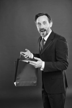 Güzel alışveriş. Şok edici bir indirim. Olgun iş adamının elinde hediye paketi kırmızı arka plan var. Alışveriş konsepti. Noel hediyesi. İyi tatiller. Mutlu adam yeni yılı kutluyor. Sevgililer Günü hediyesi.