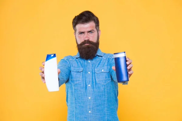 Fornire cure nutrienti. Hipster tenere prodotti per la cura dei capelli sfondo giallo. Uomo barbuto con shampoo e gel. Seleziona la cura del corpo. Lavaggio del corpo e gel. Bagno e doccia. Pelle e barba cura. Cura della pelle — Foto Stock