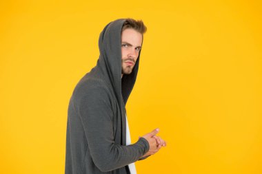 Döneceğim. Günlük yaşam için rahat kıyafetler. Moda adamı sarı arka plan. Moda bakışı. Yakışıklı adam kapüşonlu şık bir manto giyiyor. Sıradan erkek giyimi. Moda trendleri. Gençler için modern kıyafetler