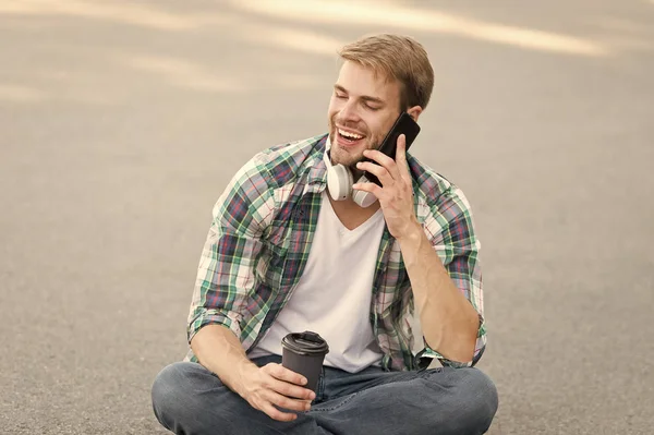 Llama a un amigo. Guy estudiante despreocupado disfrutar del café al aire libre. Balance de vida. Bienestar y salud. Tomando un café. El hombre se sienta en el suelo mientras bebe café. Relájate y recarga. Diviértete durante el descanso — Foto de Stock