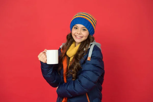 La bebida caliente está llamando. Niño feliz sostenga la taza de té fondo rojo. A los niños les gusta el chocolate caliente o la leche. Sabrosa receta de bebida. Beber sano vivir bien. Clima invernal. Bebida aromática calienta el cuerpo y el corazón —  Fotos de Stock