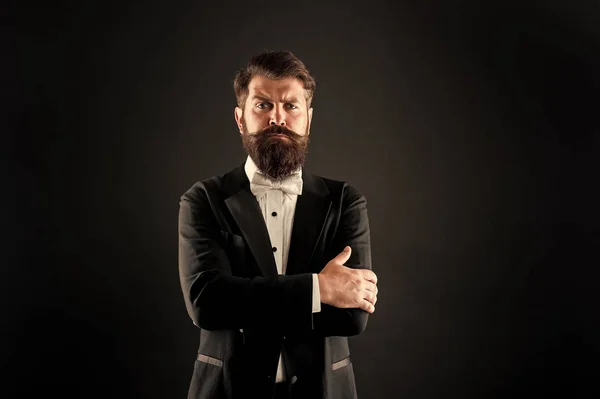 Haz una declaración. Un hombre de confianza de fondo negro. El hombre barbudo mantiene los brazos cruzados con confianza. Mirada segura de moda hipster. Un esmoquin elegante lo hace sentir seguro. Confiado en cada ocasión — Foto de Stock