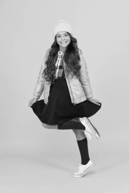 Neşeli hissediyorum. Modern kıyafet. Sevimli okul kızı kış kıyafeti. Sırt çantalı kız öğrenci kıyafeti. Moda aksesuarı. Kız gülen surat, küçük şık şirin kız örgü şapka ve ceket giyiyor.