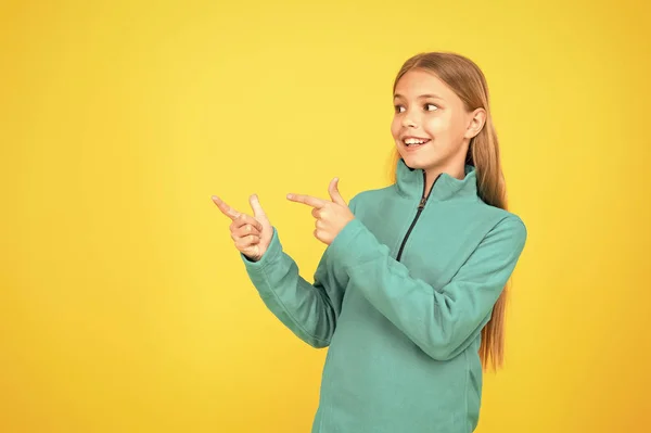 Bestellen und kaufen. glückliches Kind präsentiert Produkt auf gelbem Hintergrund. kleines Mädchen, das mit dem Finger auf etwas zeigt. Produktwerbung. Produktwerbung. Förderung von Produkt oder Dienstleistung, Kopierraum — Stockfoto