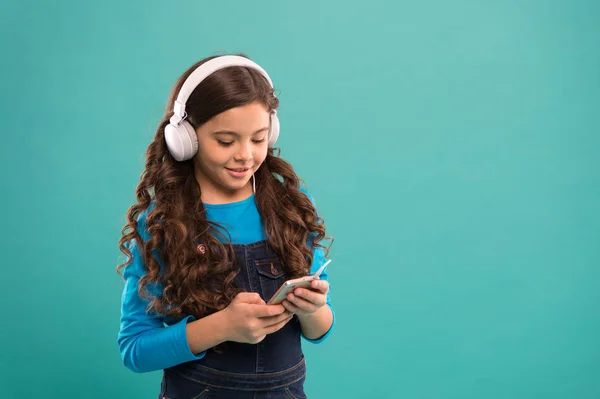 Małe dziecko zrobić listę odtwarzania na smartfonie. Mała dziewczynka trzymać odtwarzacz mp3. Wybieram ulubioną piosenkę. e-learning we współczesnym życiu. Uczennica używa nowej technologii. Dzieciak słucha muzyki w słuchawkach. przestrzeń kopiowania — Zdjęcie stockowe