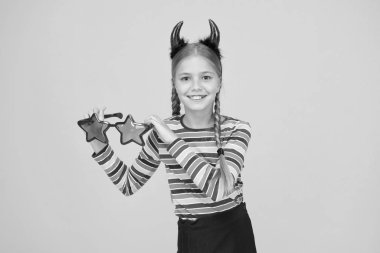 Cadılar Bayramı bu aksesuarla dolu olsun. Küçük çocuk sarı arka planda Cadılar Bayramı aksesuarı giyiyor. Küçük kız moda göz aksesuarı tutuyor. Cadılar Bayramı için parti aksesuarı