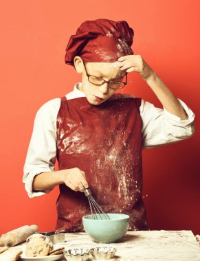Kırmızı stüdyo arka planında lekeli aşçı çocuk.