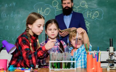 Çocuklar bilimsel deneyler yapıyor. Eğitim. Kimya laboratuvarı. Mutlu çocuk öğretmenim. Okula dönüyorum. Kimya laboratuvarında sıvılarla deneyler yapıyor. Sonuçları kontrol ediyorum.