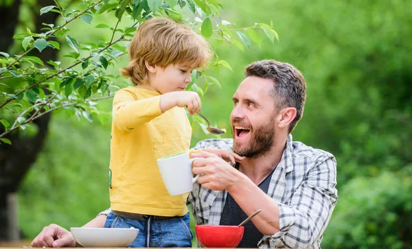 Father son eat food and have fun. Feeding baby. Menu for children. Family enjoy homemade meal. Food habits. Little boy with dad eating food nature background. Summer breakfast. Healthy food concept — Stock Photo, Image