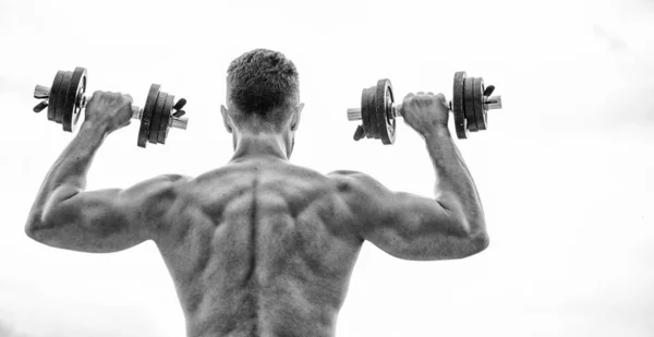 Gespierde man traint met halter achteraanzicht. Pijn is tijdelijk, trots is voor altijd. Sportman met sterke rug en armen. Sportuitrusting. Bodybuilding sport. Sport levensstijl. Dumbbell fitnessruimte — Stockfoto