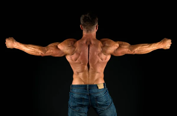 Profesyonel antrenör başarıları gösterir. Sırt egzersizleri. Vücut geliştirici mükemmel bir dikiz açısı. Güçlü vücut geliştirici kol kaslarını esnetiyor, siyah arka plan. Formda vücut geliştirici kaslı vücut gösteriyor. — Stok fotoğraf
