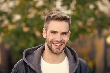 İnsanoğlu böyle görünmek ister. Sonbahar gününde mutlu bir adam. Yakışıklı adam sıradan bir şekilde gülümsüyor. Tıraşsız sakallı ve şık saç tıraşlı beyaz bir adam. Sonbahar modası. Yaşam biçimi