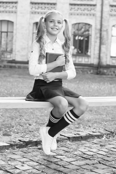 Rilassarsi nel cortile della scuola. Studente adorabile bambino in uniforme formale relax all'aperto. Studentessa rilassante sedersi sulla panchina con libro. Equilibrio di vita. Piacevoli minuti di riposo. Tempo per rilassarsi e divertirsi — Foto Stock