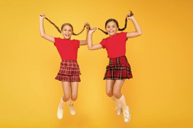 Birlikte oynuyoruz. sarı duvarda mutlu çocuklar. çocukluk mutluluğu. moda okul üniforması. komik atlama. kırmızı moda kızlar. Ingiliz cereburlu moda. damalı etekli mutlu küçük kızlar. güzellik bakmak