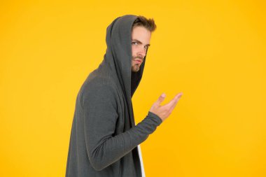 Sakin ol. Şık ve çekici bir adam. Kapüşonlu yakışıklı adam. Adam sıradan giyiniyor. Tıraşsız suratlı, beyaz bir adam. Sakallı adam sarı arka plan. Moda ve tarz