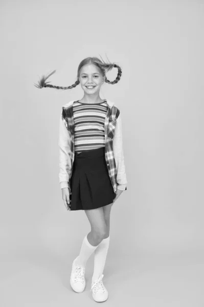 Niña. Niño pequeño con lindas trenzas peinado sobre fondo amarillo. Concepto de cuidado infantil. Chica preadolescente ropa colorida. Centro comercial para niños. Adorable cara hermosa chica. Peluquería —  Fotos de Stock