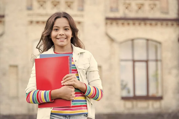 Biorąc dodatkowy kurs dla głębszego uczenia się. Edukacja szkolna. Wybór kursu. Nowoczesna edukacja. Dziecko uśmiechnięta dziewczyna szkoły uczeń trzymać skoroszytów podręczników do studiowania. Edukacja dla uzdolnionych dzieci — Zdjęcie stockowe