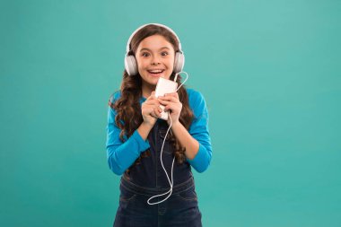 O çok mutlu. Mutlu küçük kız. Liseli kız dijital cihaz kullanıyor. Çocuklar için sıradan moda. Uzun saçlı çocuk kulaklıkla müzik dinliyor. Küçük çocuk akıllı telefondan çalma listesi yapıyor. Küçük kız mp3 oynatıcı kullan