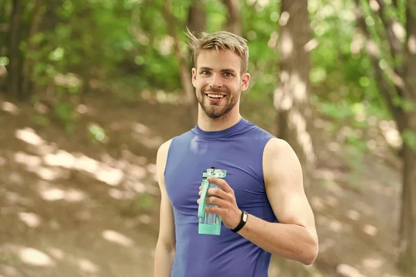 水のボトルを持つ幸せな運動人。アスリートは公園でトレーニングした後、水を飲みます。体の水分補給。スポーツと健康。スポーツウェアの男は水を飲む。トレーニング後にさわやかなビタミンドリンク。幸せな健康 — ストック写真