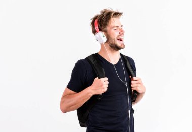 Müzik dinleyen yakışıklı öğrenci. Gençlik müziğinin tadı. Modern insan konsepti. Saç stili değiştirilmiş adam plastik kulaklık takıyor. Gittiğin her yerde müziğin tadını çıkar. Müzik uygulaması indir