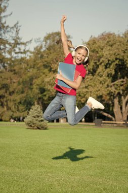Listening activities. Energetic girl listening to audio files in headphones. Cute small child practice listening comprehension on summer outdoor. Develop listening skills. Online education. Elearning