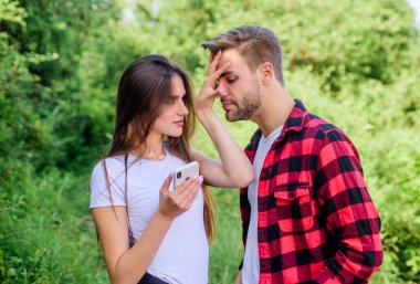 Bakma. Birbirine aşık çiftler. Blog konsepti. Çift açık havada akıllı telefon kullanıyor. Seyir subayı arıyor. İnternette romantik bir randevu. Parktaki kızın telefonunu kurcalayan adam. Kıskançlık. Kişisel alan kavramı. Kayboldum.