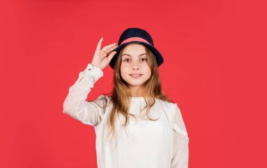 Havalı hissediyorum. Uzun saçlı çocuk şapka takıyor. Aksesuar dükkanı. Kıyafet ilhamı. Bireysel stil. Kız kırmızı arka plan takıyor. Şapkalı mutlu çocuk. Moda aksesuarı. Yaz aksesuar koleksiyonu