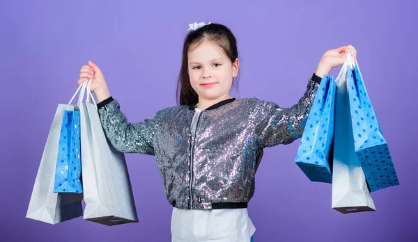 Černý pátek. Nákupní den. Dítě drží balíky. Dětská móda. Překvapivý dárek. Skvělé obchody. Skvělá volba. Dívka s nákupní tašky fialové pozadí. Nakupování a nákup. Prodej slevy — Stock fotografie