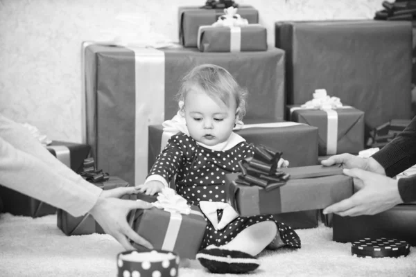 小女孩玩附近堆礼品盒。给孩子们的礼物第一个圣诞节。庆祝第一个圣诞节。与家人分享宝宝第一个圣诞节的快乐。婴儿第一个圣诞节一生中的第一次活动 — 图库照片