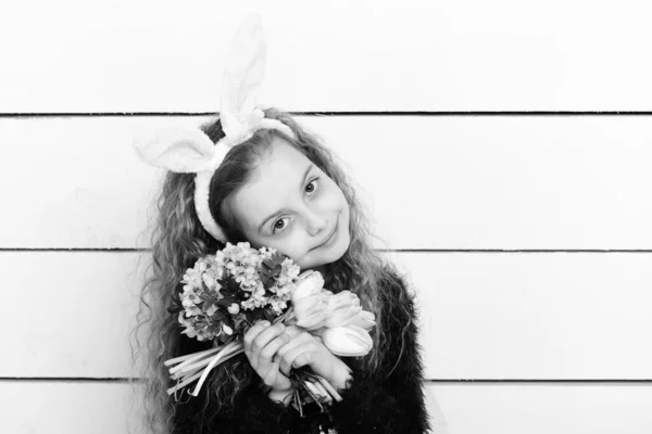 Szczęśliwa dziewczyna w wielkanocnych uszach króliczka z różowym kwiatem tulipana — Zdjęcie stockowe