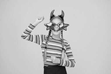 Kostüm partisine hazırlanıyorum. Sarı arka planda parti kızı. Küçük çocuklar cadılar bayramı partisi aksesuarları giyer. Cadılar Bayramı çocuğu parti havasında. Tatil kutlaması. İyi tatiller.